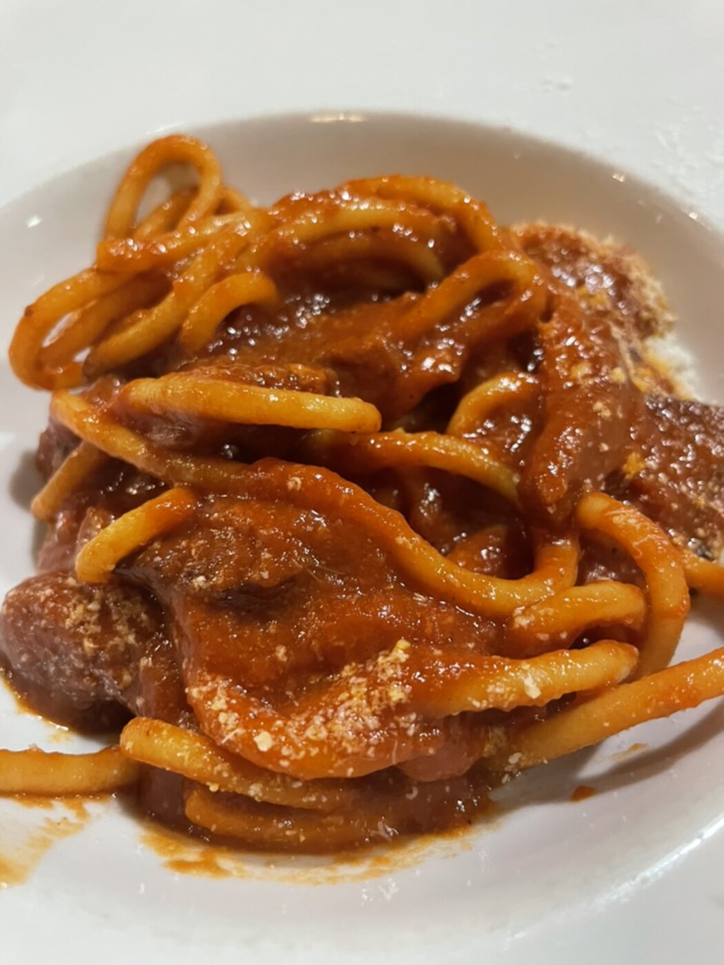 Bowl of turkey bolognese over pasta topped with grated parmesan and basil